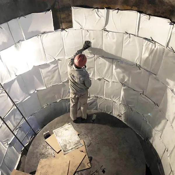 Alt text: **Worker installing white backup insulation panels inside a steel ladle lining during refractory maintenance.**